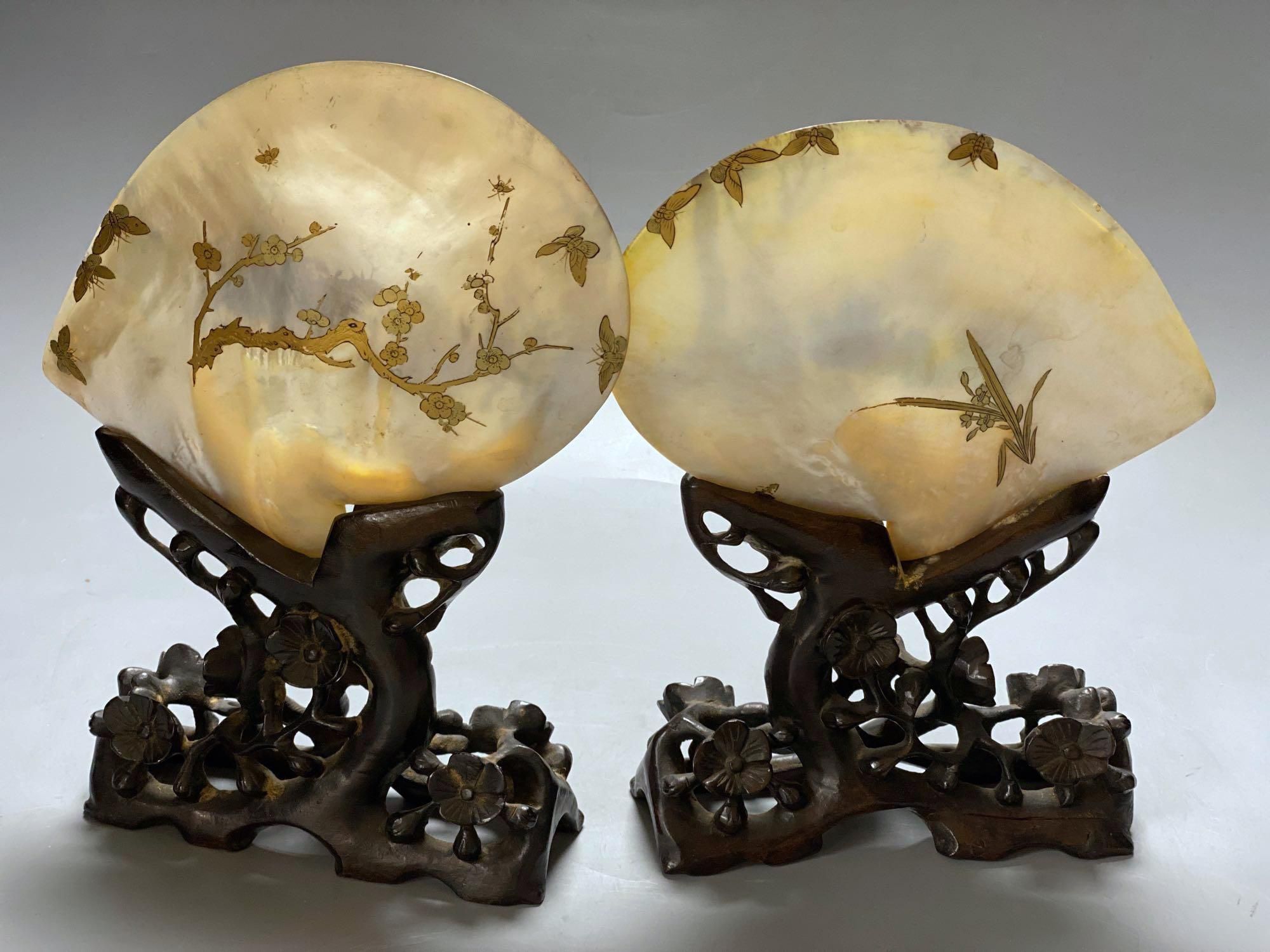 A pair of Chinese mother opearl dishes, gilt lacquered with figures and birds in landscapes, on carved hardwood stand, 26cm